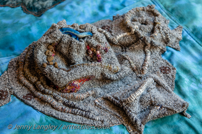 Textured volcanic island with water filled cone, fumarole and pocket.